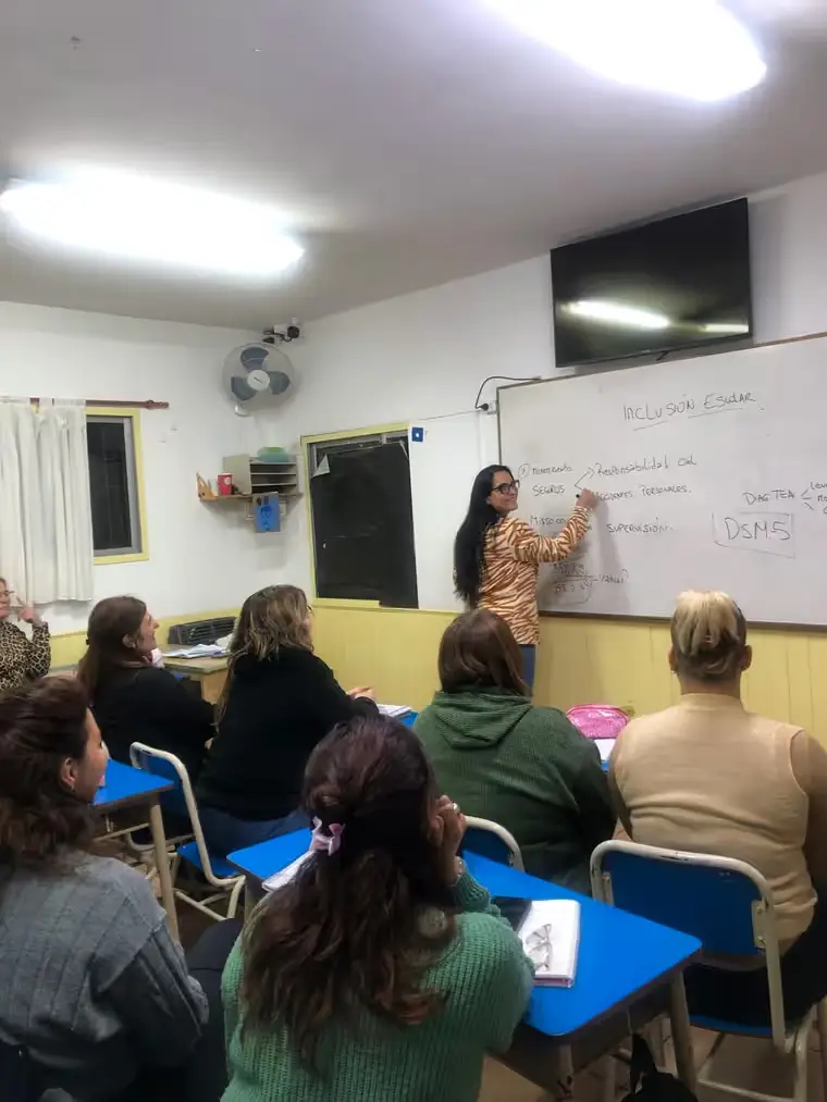 Docente dando clase sobre inclusión escolar frente al pizarrón
